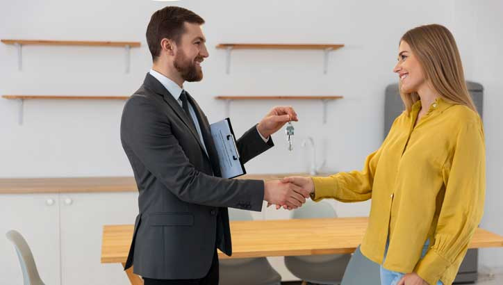 Un arrendador entregando las llaves del apartamento a su arrendataria